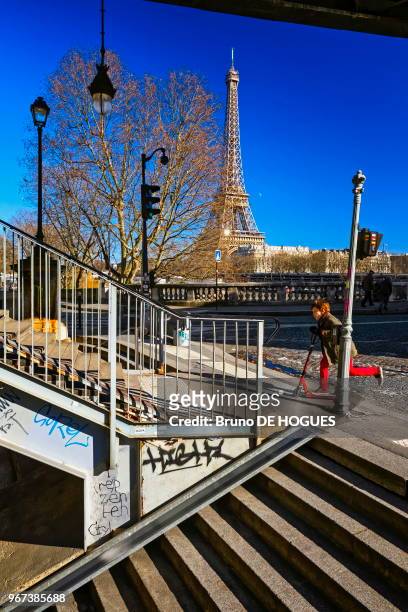 Un enfant au pantalon rouge approchant en trottinette des escaliers du Pont de Bir-Hakeim, 16 février 2016, à Paris, France.