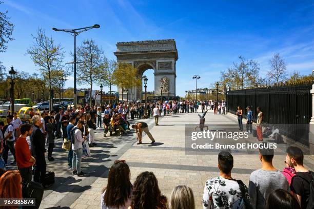 Spectacle de rue pour les touristes devant l'Arc de Triomphe à Paris.