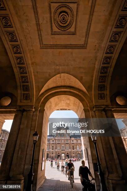 La Cour Carrée et le Pavillon de l'Horloge au Louvre, touristes à vélo visitant Paris, France.