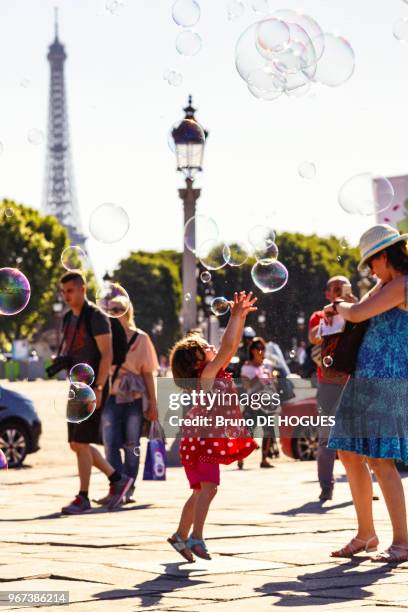 Une petite fille attrapant des bulles de savon Place de la Concorde, 26 mai 2017, Paris, France.