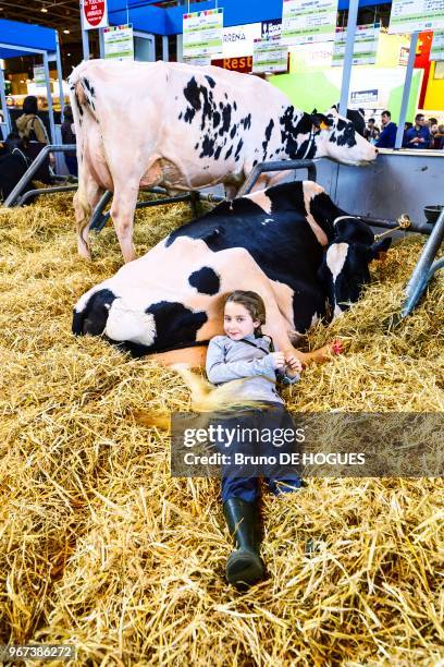 Une petite fille allongée à côté d'une vache lors du Salon International de l'Agriculture le 25 Février 2017 à Paris, France.