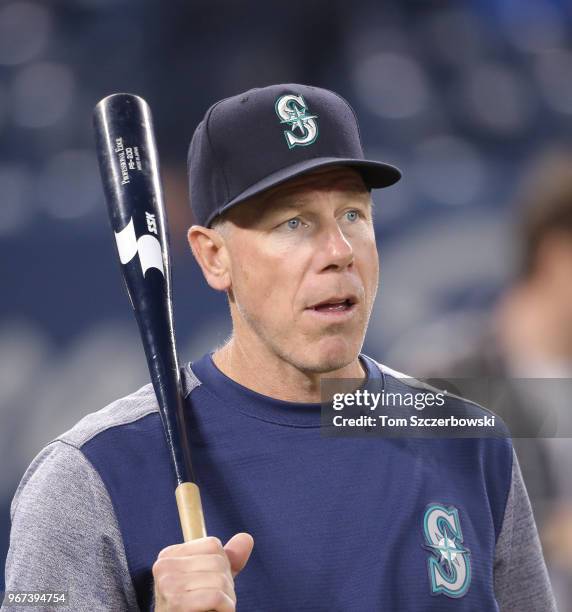 Third base coach Scott Brosius of the Seattle Mariners holds a fungo bat during batting practice before the start of MLB game action against the...