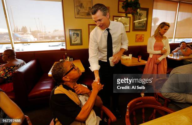 Gavin Newsom with his wife Jennifer Siebel Newsom, right, greet Ronnie Breaux, left, one of several morning diners at The Serving Spoon Restaurant in...