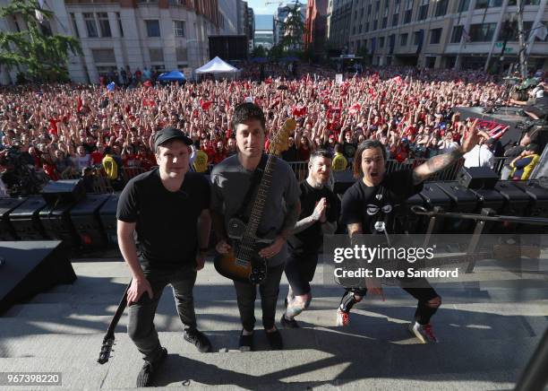 Patrick Stump, Joe Trohman, Andy Hurley and Pete Wentz of Fall Out Boy pose together onstage after performing in the pregame concert on the steps of...