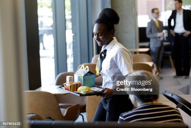 An employee brings an order to customers at the restaurant inside the new McDonald's Corp. Headquarters in Chicago, Illinois, U.S., on Monday, June...