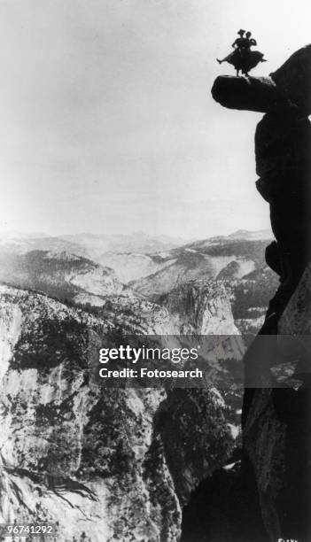 Distant silhouette view of Kitty Tatch and friend photographed by George Fiske as they dance on the overhanging rock at Glacier Point, Yosemite,...