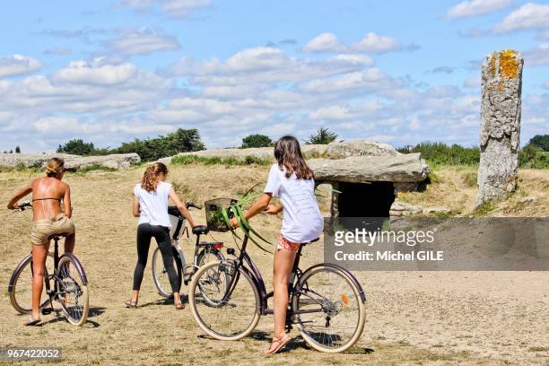 Touristes à vélos visitant un monument mégalithique classé "Monument Historique", les Pierres-Plates, 16 Juillet 2017, Locmariaquer, Golfe du...