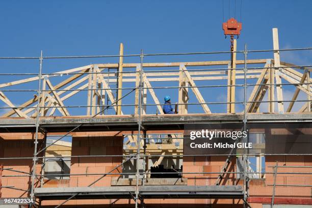 Charpentier posant une charpente en bois sur un immeuble en construction, 19 mars 2012, Le Mans, France.