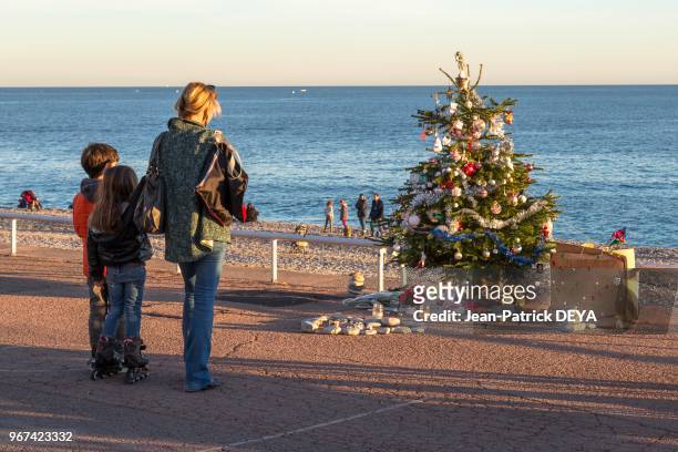 Famille se recueillant devant un arbre de Noel sur la Promenade des Anglais, 28 décembre 2016, en hommage à un enfant victime de l'attentat du 14...