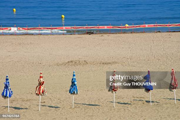 Parasols à rayures typiques sur une plage fermée au public, Trouville sur Mer, France.