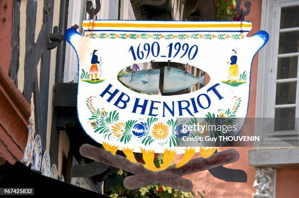 Enseigne de magasin 'HB Henriot' avec des motifs en céramique.