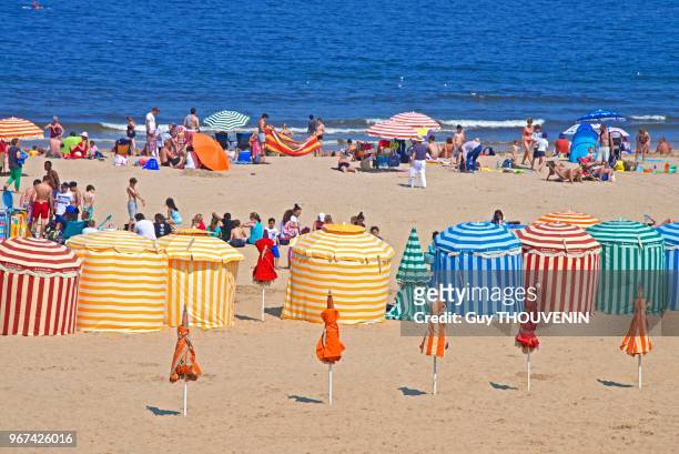 Tentes à rayures typiques et vacanciers sur la plage, Trouville sur Mer, France.