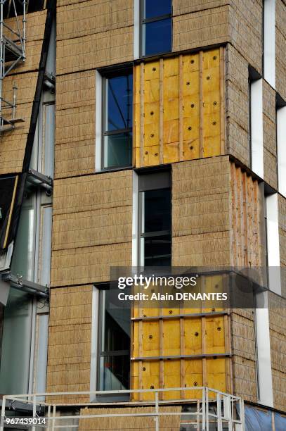 Isolation thermique par l'exterieur avec un bardage en chaume recouvrant les panneaux de laine de verre sur le chantier d'un batiment en...