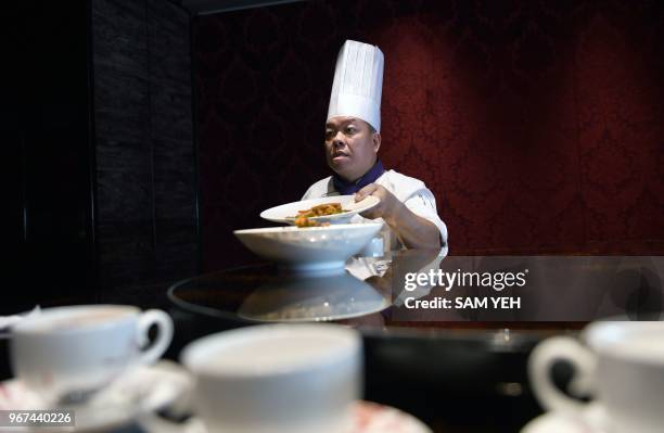 This picture taken on May 17, 2018 shows Ken Chan, the executive chef at the five-star hotel restaurant Le Palais in Taipei, displaying two dishes...