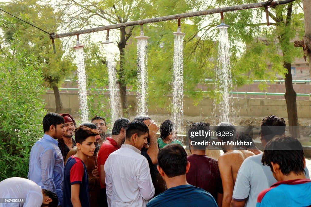 People taking bath under the showers beside the canal in hot temperature during fast in Ramadan
