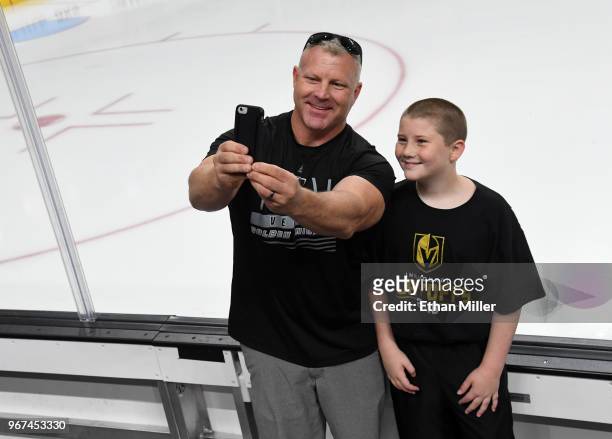 Vegas Golden Knights fans Darrell Garvin and his son Gage Garvin both of Nevada, pose for selfies next to the boards during a Golden Knights road...