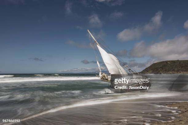 washed ashore sailboat on beach - jasondoiy stock pictures, royalty-free photos & images