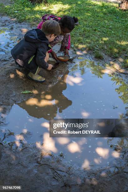 Deux enfants jouant près d'une flaque d'eau, Ecole Steiner Waldorf le 22 juin 2015, Saint-Genis Laval dans le département du Rhône, France.