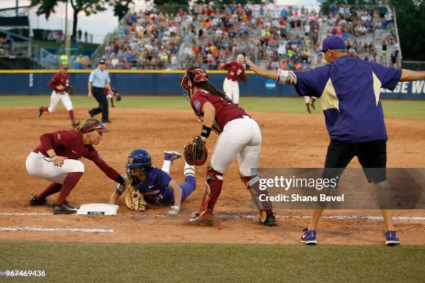 Kelly Burdick of the Washington Huskies dives safely back into first base under the tag of Carsyn Gordon of the Florida State Seminoles during the...