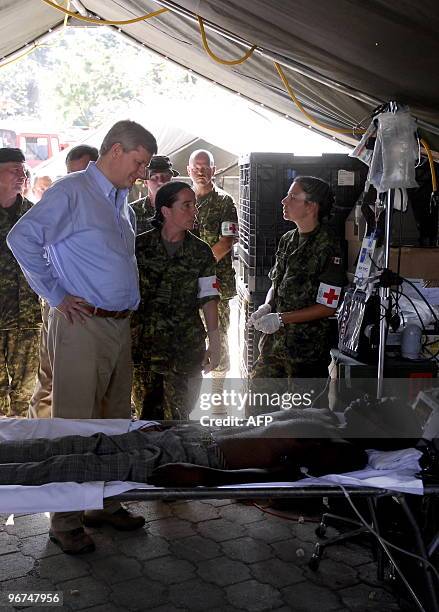 Canada's Prime Minister Stephen Harper looks at a victim of Haiti's earthquake on February 16, 2010 during a visit to a Canadian Army field hospital...