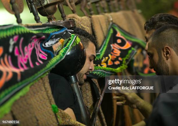 An iranian man carries an alam is helped by shiite muslim mourners to keep his balance on ashura, the day of the death of hussein, isfahan province,...