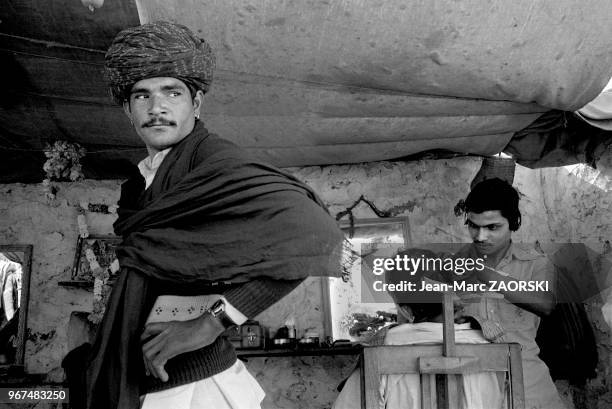 Scène de vie quotidienne dans l'échoppe d'un coiffeur, le 28 novembre 1982 à Pushkar, Rajasthan, Inde.