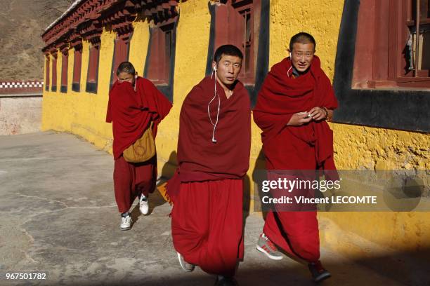 Vêtus de leurs habits traditionnels et de baskets fabriquées en Chine, trois moines bouddhistes tibétains se rendent à la grande cérémonie de la...