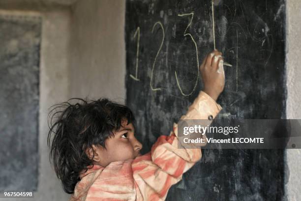 Enfant indien écrivant à la craie sur un tableau noir lors d?un cours d?alphabétisation donné par une ONG locale à des enfants défavorisés à Udaipur,...