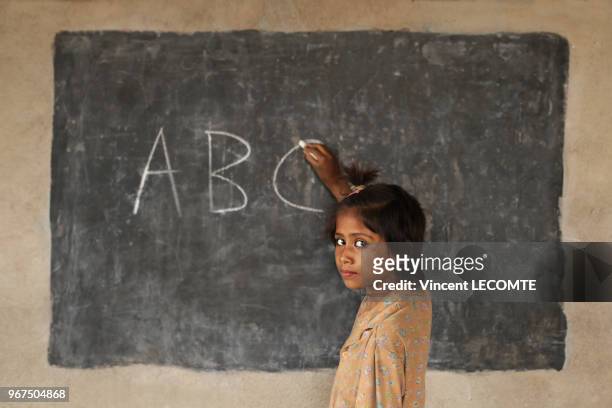 Fillette indienne écrivant « ABC » à la craie sur un tableau noir lors d?un cours d?alphabétisation donné par une ONG locale à des enfants...
