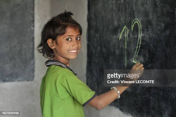 Enfant indien écrivant à la craie sur un tableau noir lors d?un cours d?alphabétisation donné par une ONG locale à des enfants défavorisés à Udaipur,...