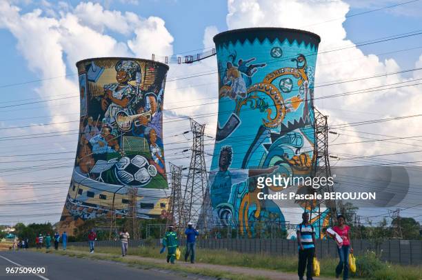 Gens marchant devant les 2 tours de refroidissement plus en activite, fresques murales representant les moments et les gens importants de Soweto,...