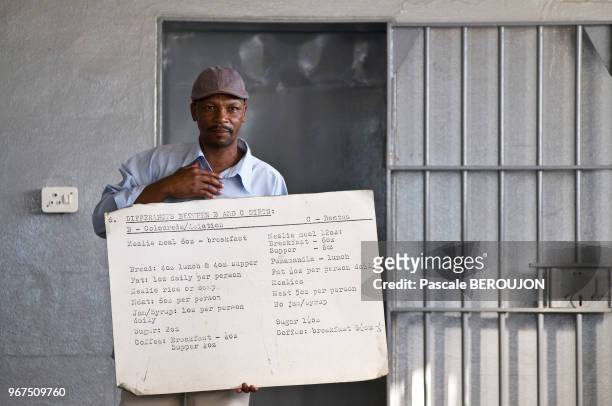 Ancien prisonnier, aujourd'hui guide à la prison de Robben island devenu Monument National et musée, montrant le panneau des portions de nourriture...