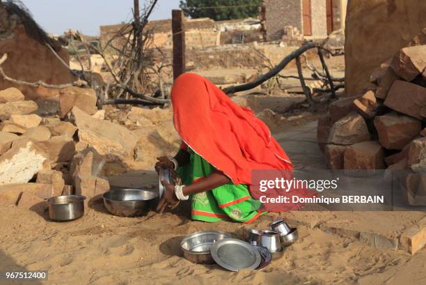 Jeune femme indienne faisant la vaisselle dans un petit village du désert du Thar, 31 décembre 2016, Jaisalmer, Rajasthan, Inde.