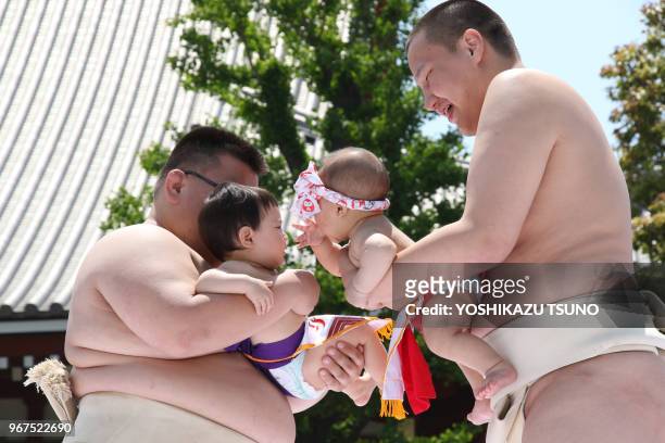Bébés tenus par des lutteurs sumo s'affrontent en criant le plus fort possible dans le temple Sensoji à Tokyo le 30 avril 2017, Japon. Les parents...