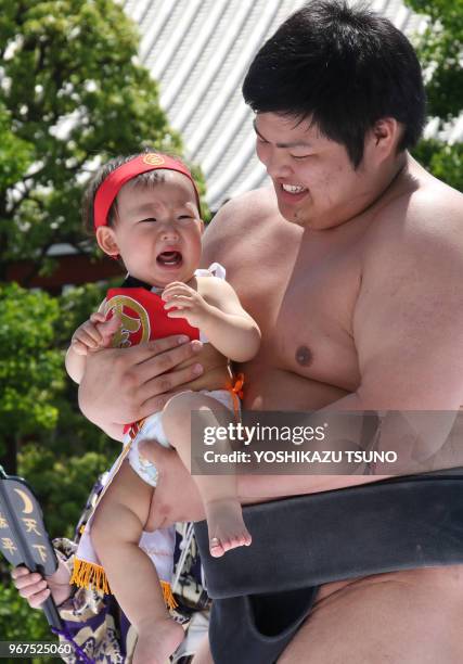 Bébé tenu par un lutteur sumo lors d'une compétition de cri dans le temple Sensoji à Tokyo le 30 avril 2017, Japon. Les parents japonais croient que...