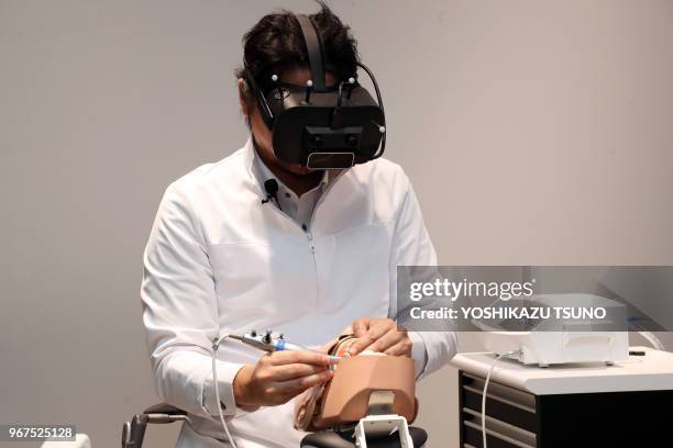 Japanese dentist wearing a head mount display demonstrates a dental treatment on a dammy using a technology of mexed reality in Tokyo on April 21,...