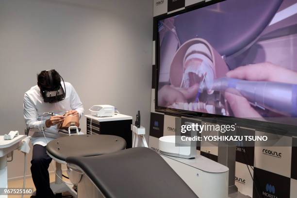 Japanese dentist wearing a head mount display demonstrates a dental treatment on a dammy using a technology of mexed reality in Tokyo on April 21,...