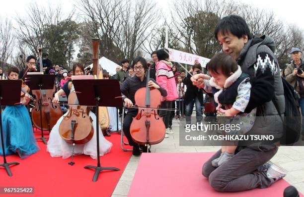 Un homme aide son bébé à diriger un orchestre de 40 musiciens au parc Ueno à Tokyo le 31 mars 2017 lors du 'Tokyo Spring Festival - Tokyo 0pera...