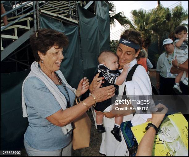 After winning her Ericsson Open Doubles match, Aranxta Sanchez Vicario holds a friends baby, as her mother Marisa keeps an eye on the baby.