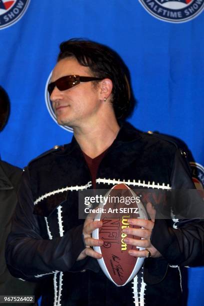 ETrade Super Bowl XXXVI Halftime Show news conference featuring the Legendary Rock Band U2 with Bono. Bono holding NFL football with both hands..said...