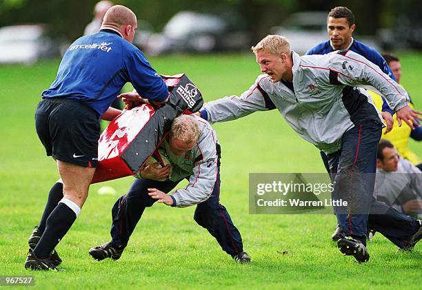 Neil Back of the England Rugby Team is tackled by Phil Vickery and Lewis Moody during a Training Session at Sandhurst Acadamy in Camberley, Surrey,...