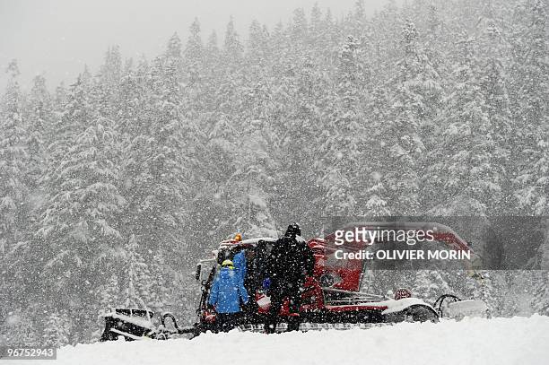 Race officials are seen talking next to a chain cat as the Alpine skiing competitions are postponed due to weather conditions at the Whistler...