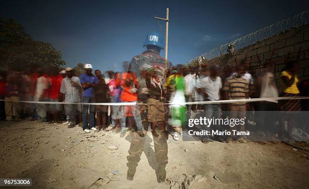 United Nations soldier from Sri Lanka keeps watch as earthquake survivors gather outside a food distribution point February 8, 2010 in...