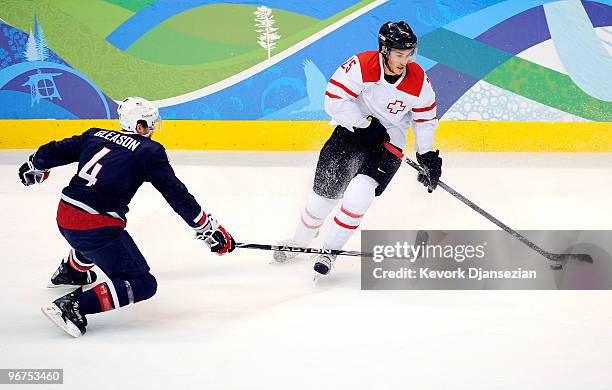 Thibaut Monnet of Switzerland controls the puck against Tim Gleason of The United States during the ice hockey men's preliminary game between USA and...