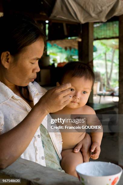 Femme donnant à manger à son enfant dans une campagne dans les environs de Siem Reap en mars 2012, Cambodge.