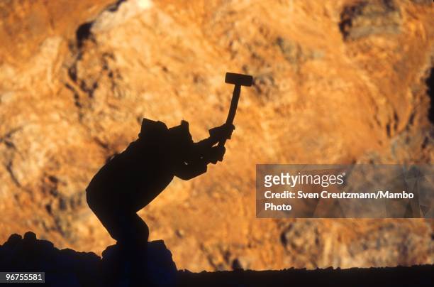 The sun rises as a worker swings a pickaxe to hit the rocks that bear Lapis Lazuli stone in the Flores de Los Andes mine, located at 3,700 meter high...