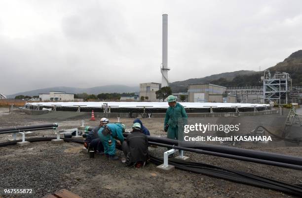 Ouvriers installant un réservoir de cultures d'algues marines de 40 mètres de diamètre, pour des recherches de carburant vert par la société J-Power...