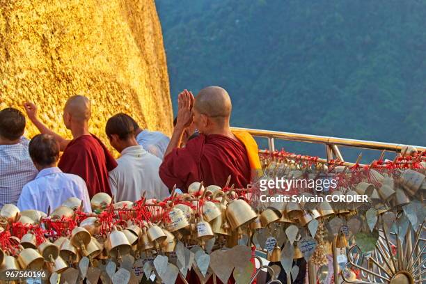 Myanmar , état de Môn, le Rocher d'Or de Kyaiktiyo, Pélerins en dévotion devant le lieu sacré, certains collent des feuilles d'or sur le rocher....