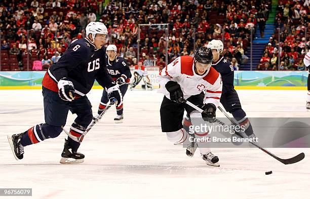 Roman Wick of Switzerland controls the puck as Erik Johnson of The United States closes in during the ice hockey men's preliminary game between USA...