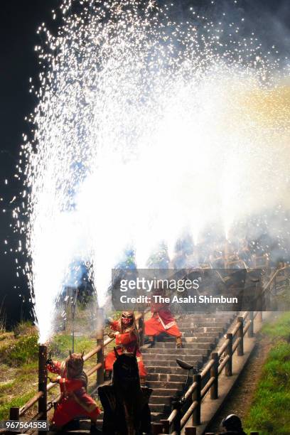 People wearing ogre masks hold the Tezutsu fireworks are seen at the observation deck of Jigokudani in the Noboribetsu Hot Spring on June 1, 2018 in...